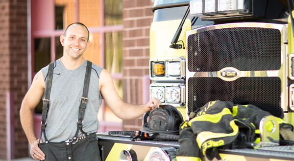Fireman standing next to a firetruck.